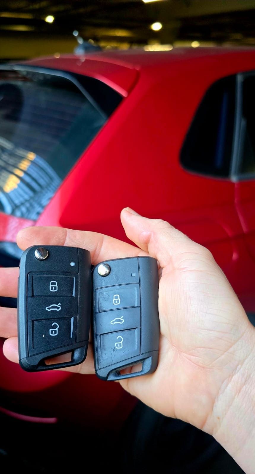 Duas chaves canivete em frente a um carro vermelho