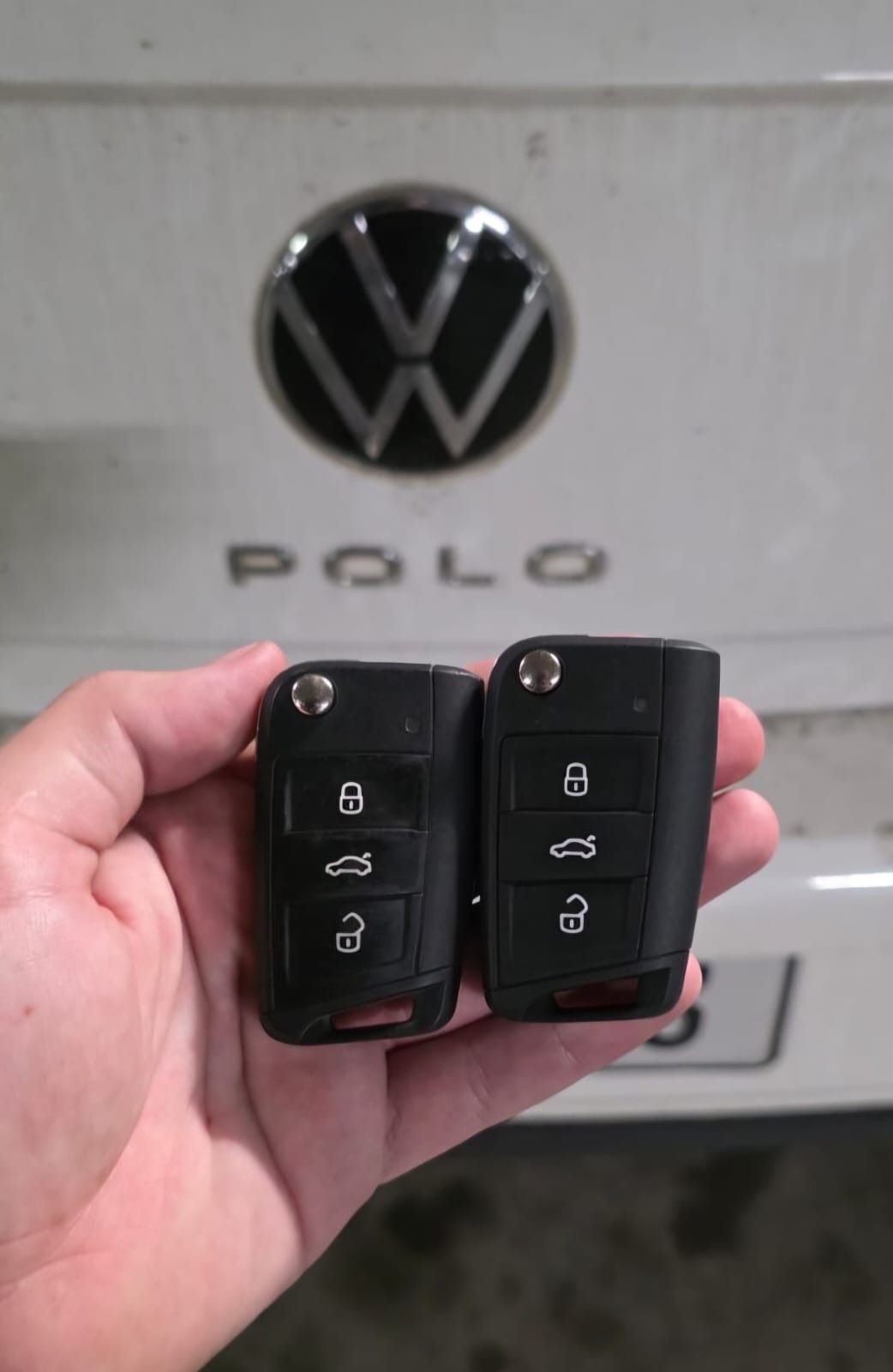 Duas chaves canivete em frente ao emblema Polo de um carro branco