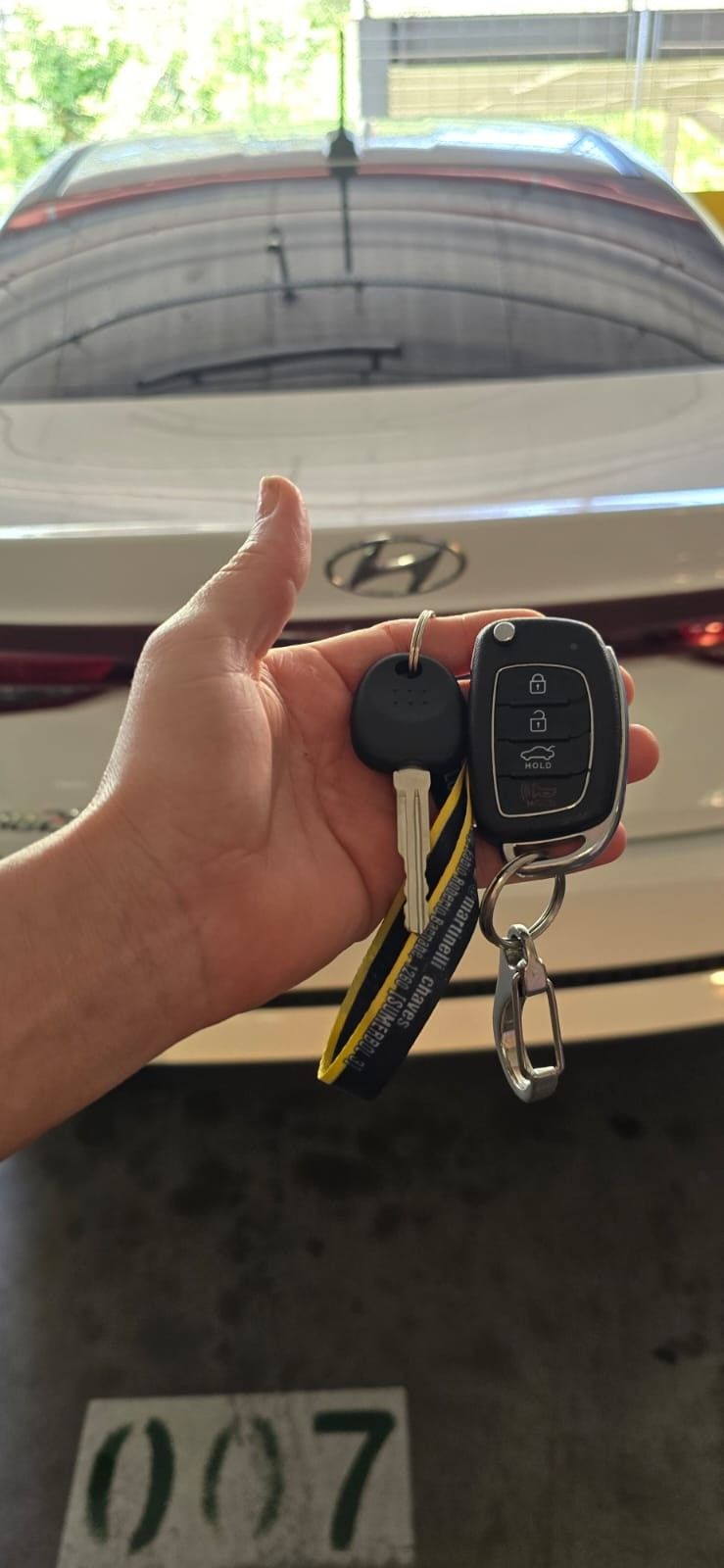 Chave com lâmina e chave canivete em frente ao emblema Hyundai do veículo