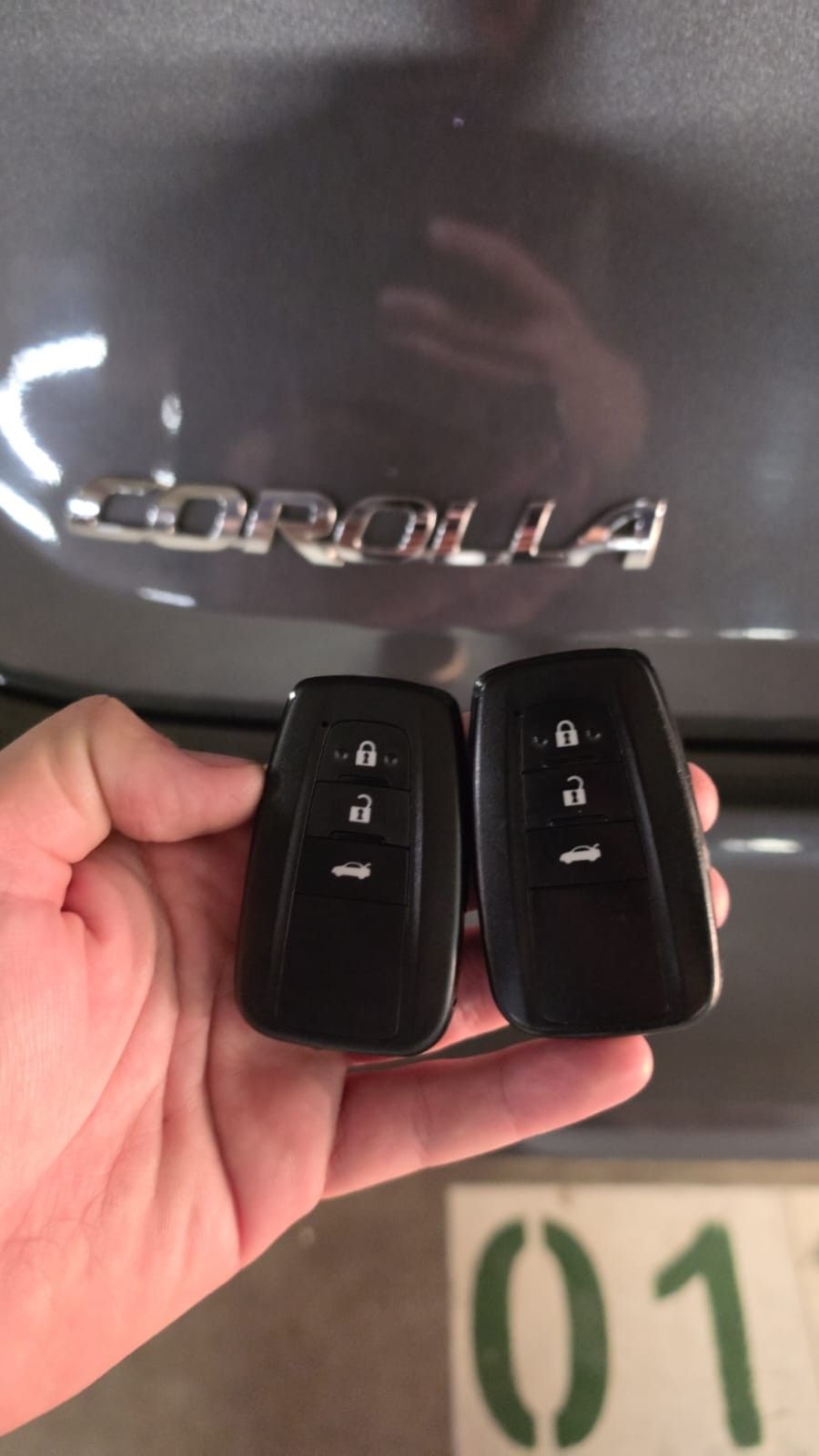 Duas chaves presenciais Toyota em frente ao emblema Corolla